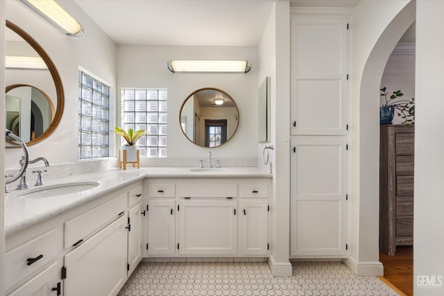 full bath featuring double vanity, baseboards, and a sink