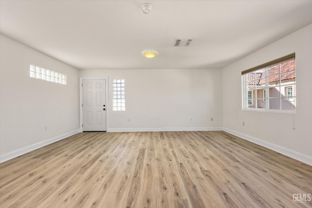 empty room with baseboards, visible vents, and light wood-type flooring