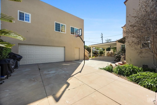 view of side of home with concrete driveway, a garage, and stucco siding