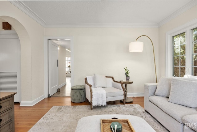 living room featuring baseboards, wood finished floors, arched walkways, and ornamental molding