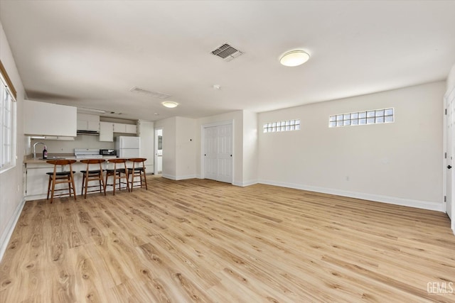 living area featuring visible vents, light wood-style flooring, and baseboards