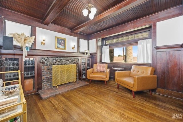 sitting room with a tile fireplace, a notable chandelier, wood finished floors, wood ceiling, and beam ceiling