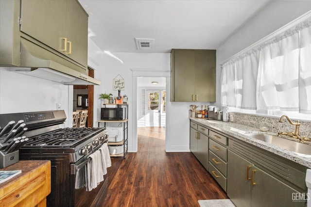 kitchen with black microwave, a sink, gas stove, dark wood finished floors, and green cabinetry