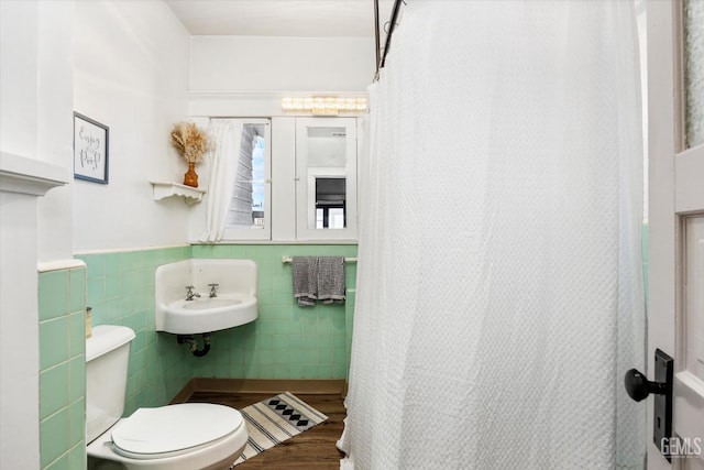 bathroom featuring tile walls, a shower with shower curtain, toilet, wainscoting, and wood finished floors