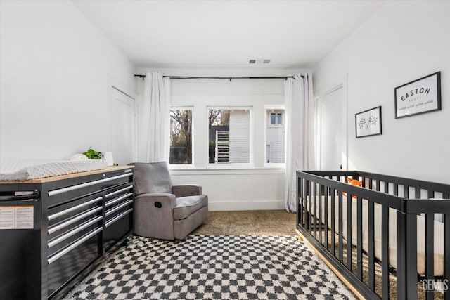 bedroom featuring a nursery area, carpet flooring, visible vents, and baseboards