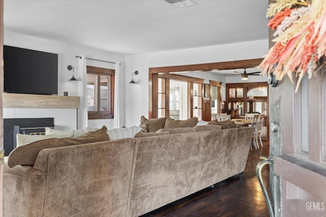 living area featuring a ceiling fan, dark wood finished floors, visible vents, and a fireplace