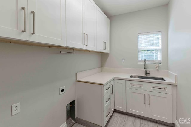 clothes washing area featuring electric dryer hookup, cabinet space, and a sink