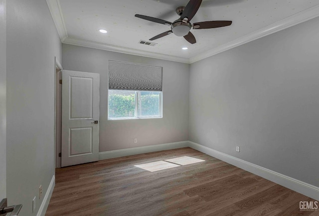 spare room featuring wood finished floors, visible vents, crown molding, and a ceiling fan