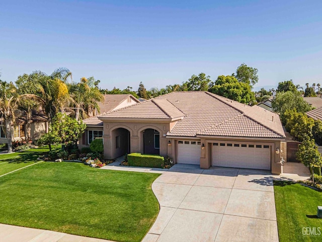 mediterranean / spanish house with stucco siding, a tiled roof, a front lawn, concrete driveway, and an attached garage