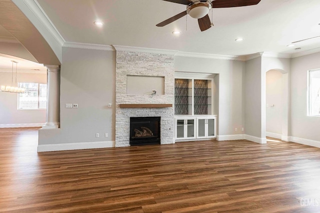 unfurnished living room with ceiling fan, a stone fireplace, wood finished floors, and baseboards