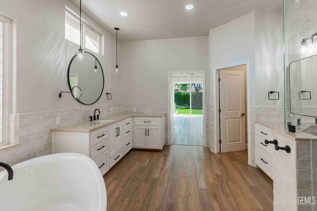 bathroom featuring recessed lighting, tile walls, a freestanding tub, wood finished floors, and vanity