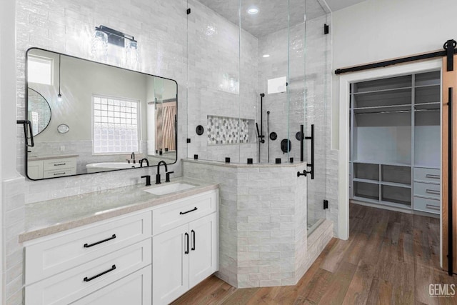bathroom featuring wood finished floors, a shower stall, and vanity