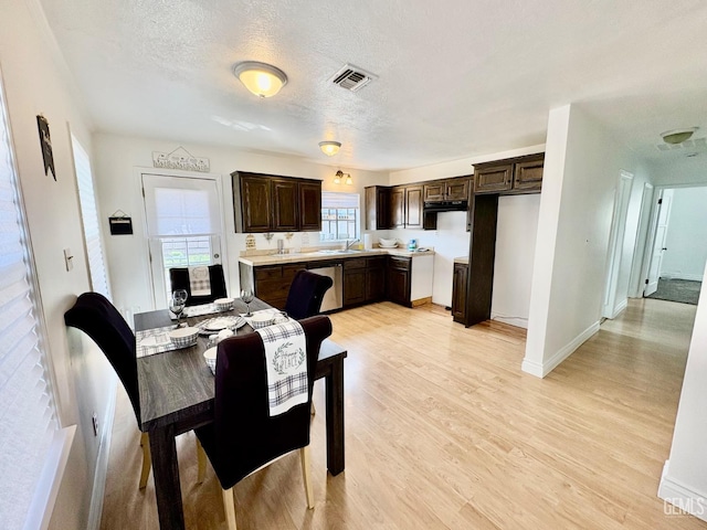 dining area featuring light wood-style floors, baseboards, visible vents, and a textured ceiling