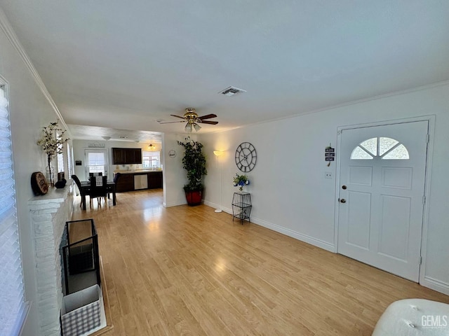 entryway featuring crown molding, visible vents, light wood-style flooring, a ceiling fan, and baseboards