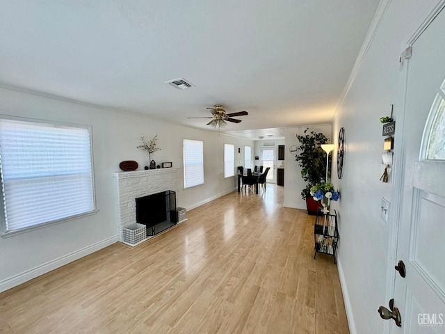 foyer entrance with ceiling fan, a fireplace, visible vents, baseboards, and light wood-style floors