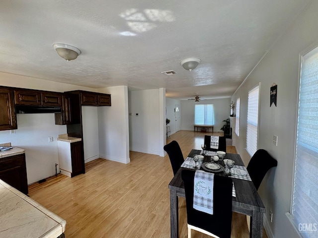 dining area with light wood finished floors, visible vents, a ceiling fan, a textured ceiling, and baseboards