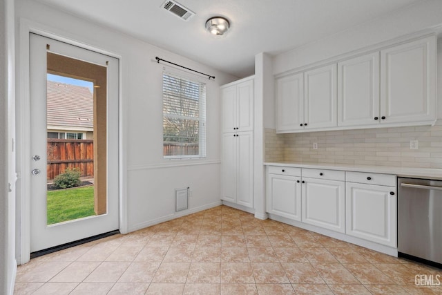 interior space with backsplash, light countertops, visible vents, stainless steel dishwasher, and white cabinetry