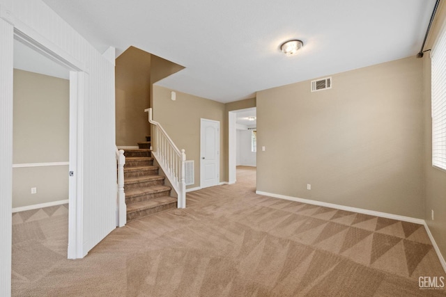unfurnished living room featuring carpet floors, visible vents, baseboards, and stairway