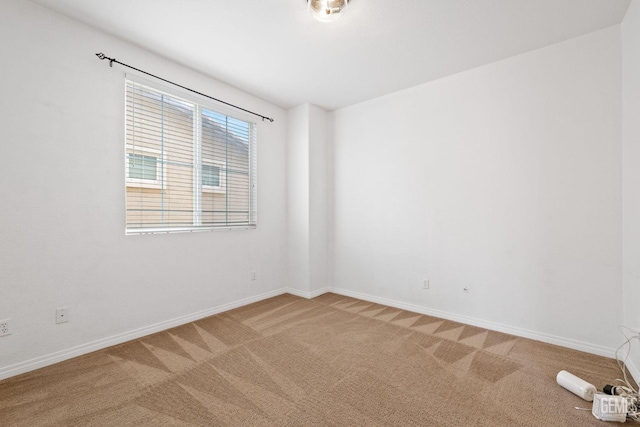 unfurnished room featuring light carpet and baseboards