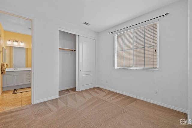 unfurnished bedroom featuring light carpet, baseboards, and a closet