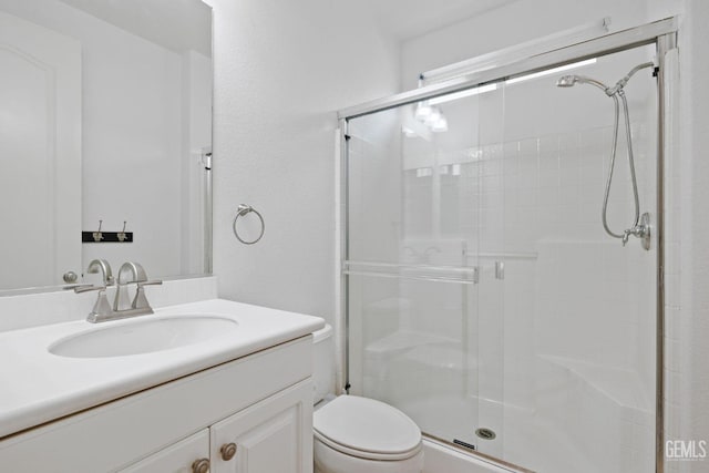 bathroom featuring a shower stall, toilet, and vanity