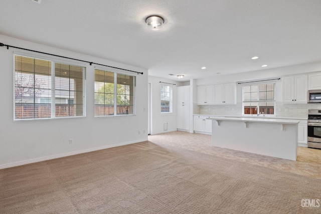 unfurnished living room with baseboards, recessed lighting, and light colored carpet