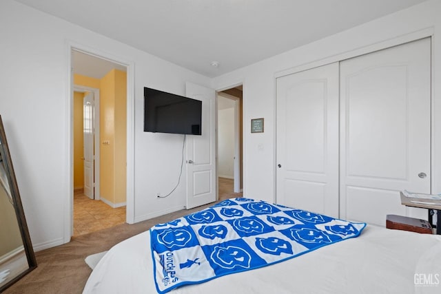 carpeted bedroom with a closet and baseboards