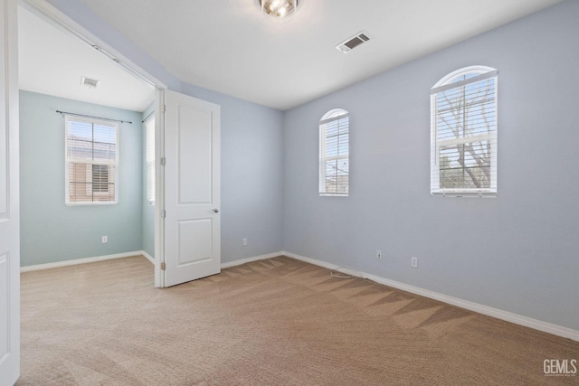 unfurnished room with visible vents, baseboards, and light carpet