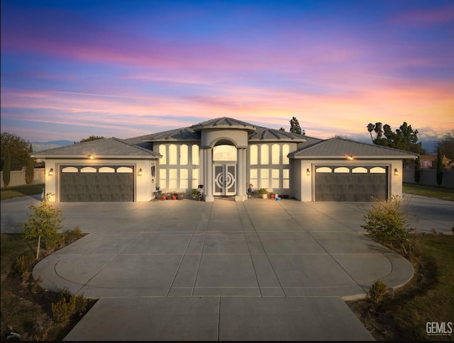 prairie-style home featuring concrete driveway, an attached garage, and stucco siding