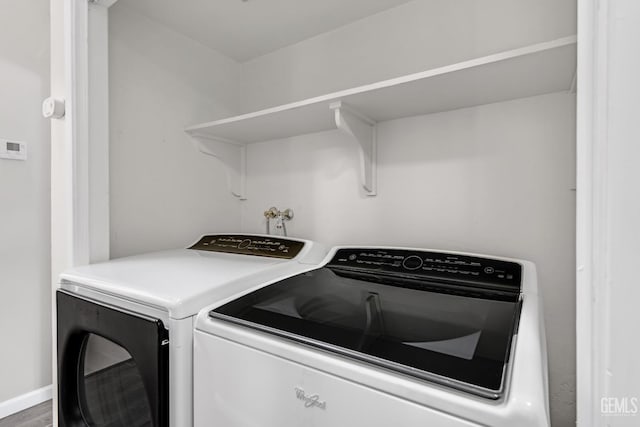 laundry area with laundry area, baseboards, wood finished floors, and washing machine and clothes dryer