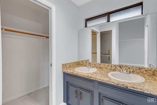 full bath featuring a walk in closet, marble finish floor, a sink, and double vanity