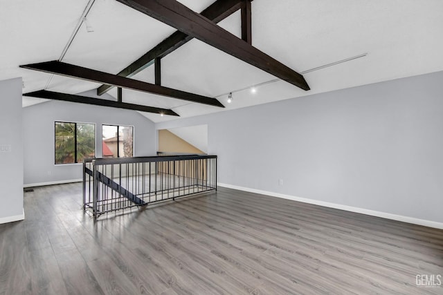 unfurnished room featuring lofted ceiling with beams, rail lighting, baseboards, and wood finished floors