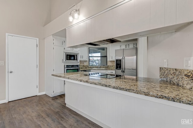 kitchen featuring tasteful backsplash, a peninsula, light stone countertops, stainless steel appliances, and white cabinetry