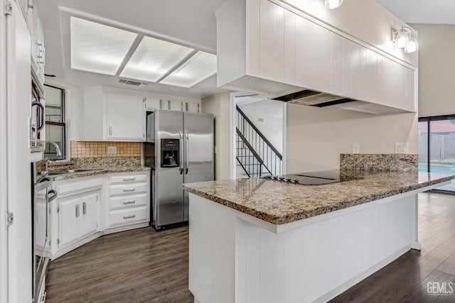 kitchen featuring stainless steel appliances, light stone counters, a peninsula, and white cabinetry