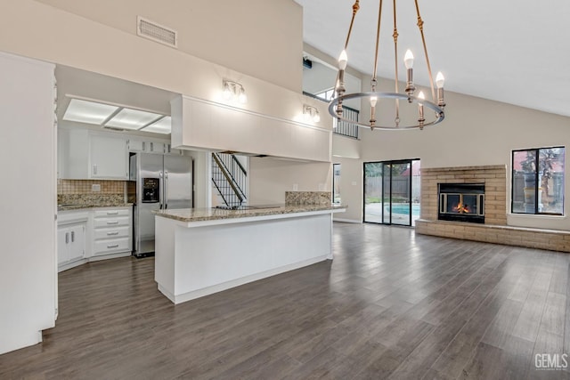 kitchen with stainless steel fridge, visible vents, white cabinets, open floor plan, and hanging light fixtures