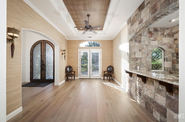 12603 Clay Creek Ct, Bakersfield, CA 93312 - entryway with french doors, a tray ceiling, arched walkways, light wood finished floors, and ornamental molding