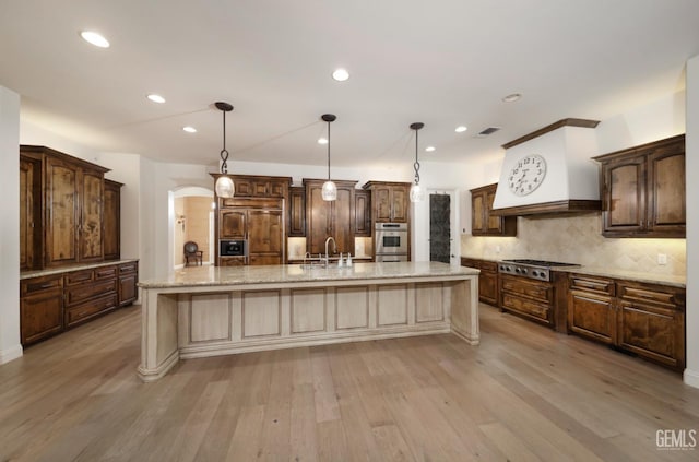 12603 Clay Creek Ct, Bakersfield, CA 93312 - kitchen with stainless steel appliances, light wood-type flooring, backsplash, a large island, and recessed lighting