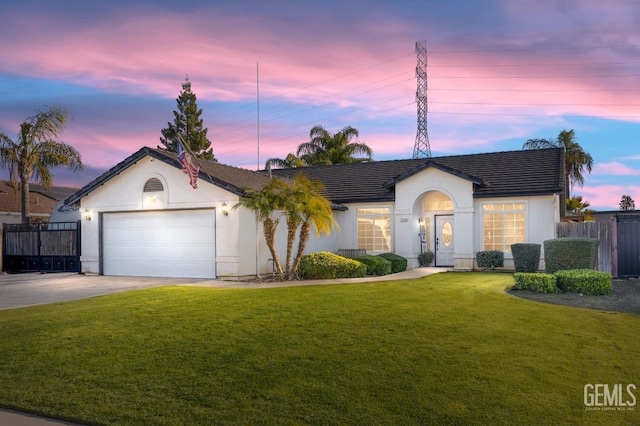 ranch-style house with a garage, driveway, a lawn, fence, and stucco siding