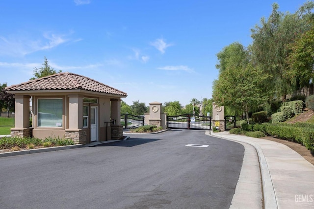 view of road with sidewalks, curbs, a gated entry, and a gate