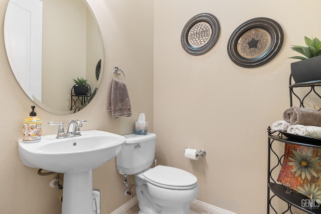 half bath featuring a sink, baseboards, and toilet