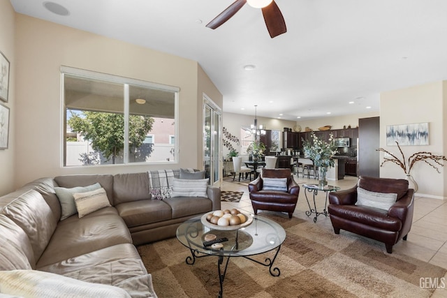 living area featuring light tile patterned flooring, ceiling fan with notable chandelier, and recessed lighting