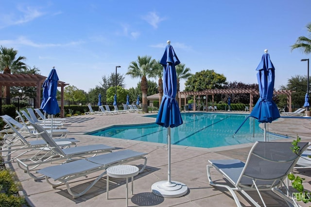 community pool with a patio area, a pergola, and fence