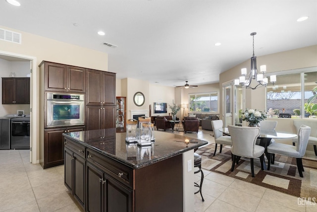 kitchen featuring light tile patterned floors, visible vents, oven, a kitchen bar, and a center island