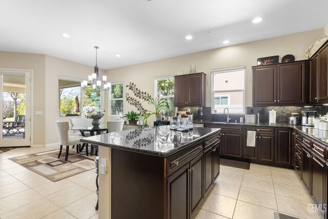 kitchen featuring a kitchen island, backsplash, recessed lighting, an inviting chandelier, and light tile patterned flooring