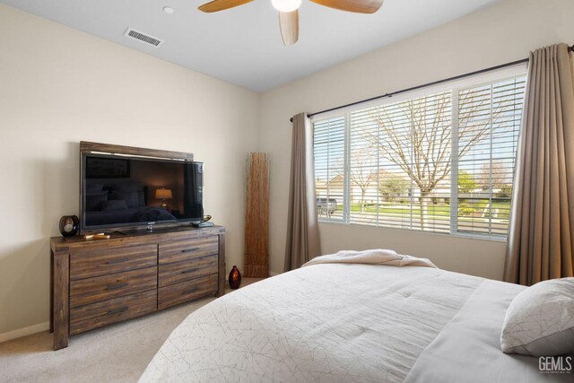 carpeted bedroom featuring a ceiling fan, visible vents, and baseboards