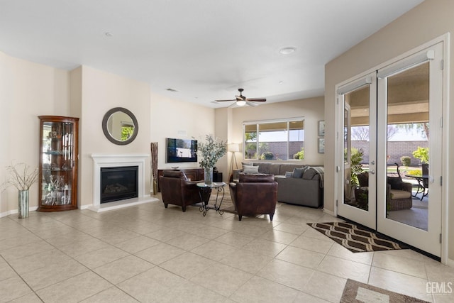 living room with light tile patterned floors, baseboards, ceiling fan, french doors, and a glass covered fireplace