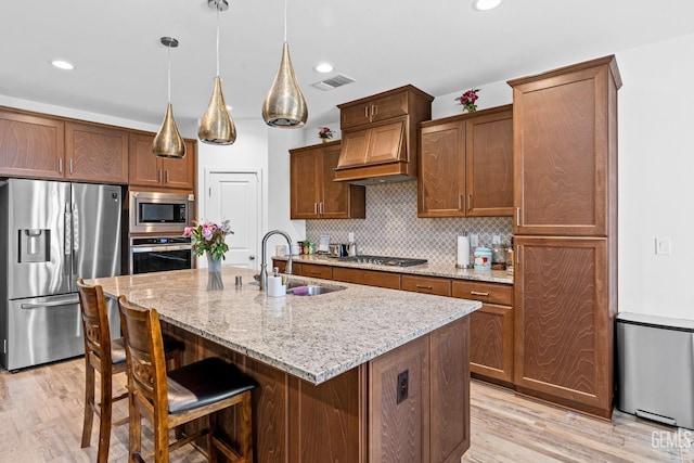 7900 Linden Tree Ave, Bakersfield, CA 93313 - kitchen with stainless steel appliances, visible vents, a sink, light wood-type flooring, and custom range hood