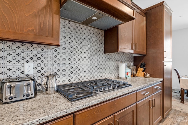 7900 Linden Tree Ave, Bakersfield, CA 93313 - kitchen featuring stainless steel gas stovetop, extractor fan, brown cabinets, and decorative backsplash