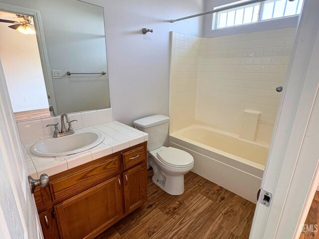 9057 Mackenzie Ct, Bakersfield, CA 93306 - bathroom featuring wood finished floors, toilet, a ceiling fan, vanity, and bathtub / shower combination