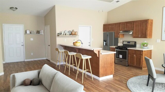 9057 Mackenzie Ct, Bakersfield, CA 93306 - kitchen with stainless steel appliances, light wood finished floors, a peninsula, a breakfast bar area, and light countertops